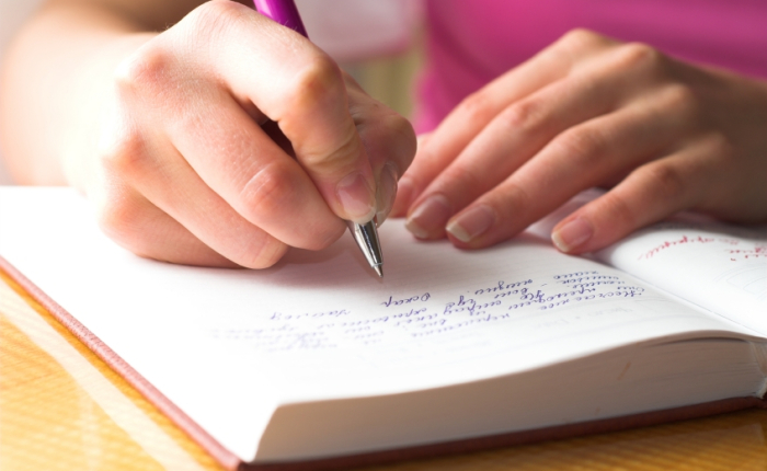 Young female is writing notes and planning her schedule.