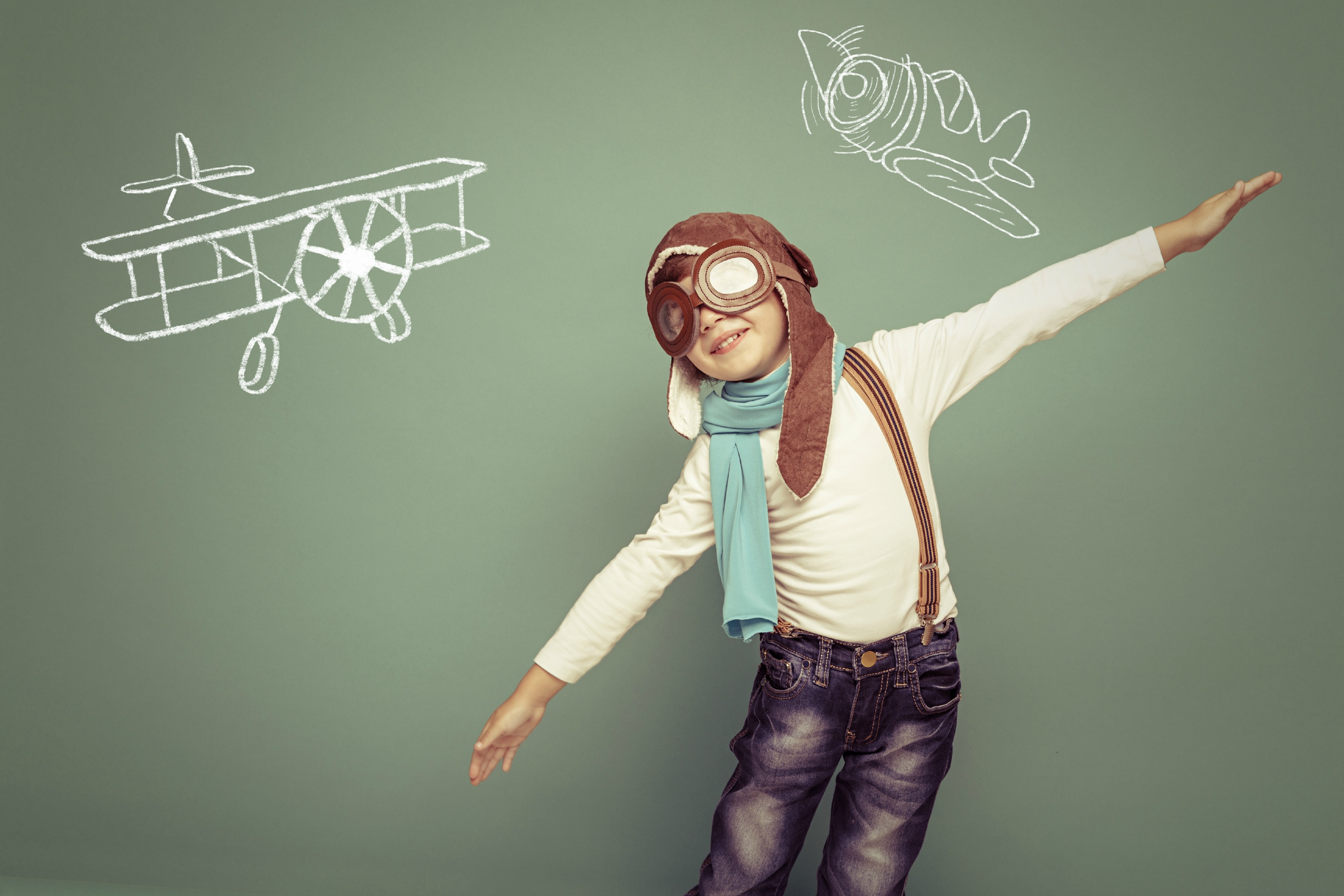 Cheerful smiling kid (boy)l in helmet on a green background. Vintage pilot (aviator) concept